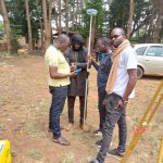 Participants apprenant à manipuler une canne GNSS avec son récepteur sur le terrain