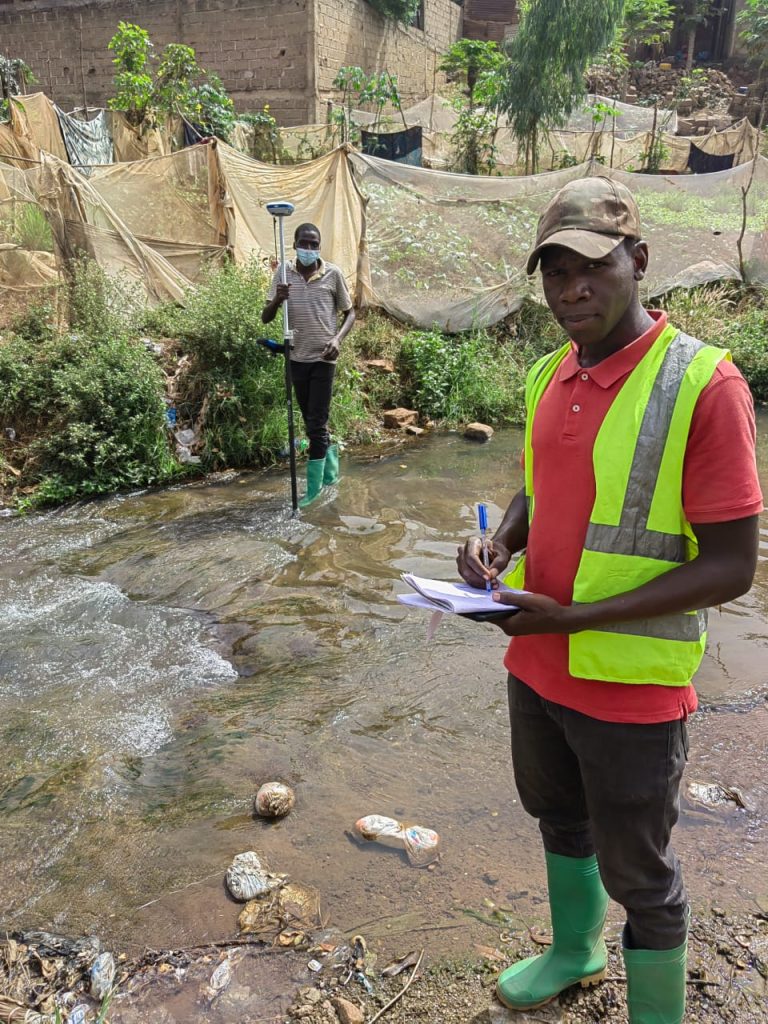 Deux techniciens relevant une section de cours d'eau, l'un à la canne GNSS, l'autre au carnet